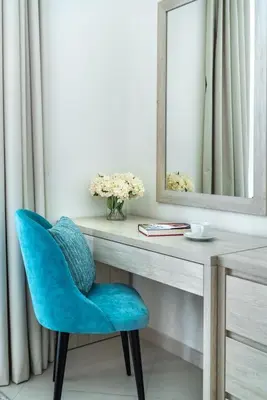 a blue chair sitting next to a desk with a mirror at Modern 1BR Seven Palm Private Beach Infinity Pool in Dubai