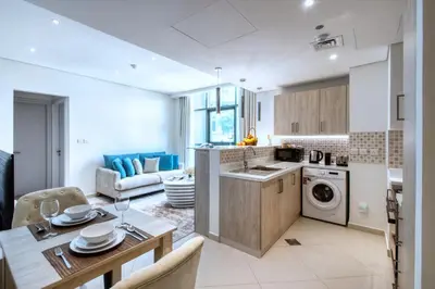 a kitchen and living room with a table and a kitchen and a dining room at Modern 1BR Seven Palm Private Beach Infinity Pool in Dubai
