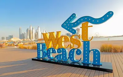 a sign for a west beach with a city in the background at Modern 1BR Seven Palm Private Beach Infinity Pool in Dubai