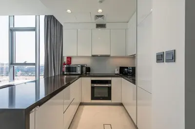 a kitchen with white cabinets and a large window at Spacious I Burj Khalifa View I District One in Dubai