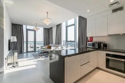 a kitchen with white cabinets and a living room at Spacious I Burj Khalifa View I District One in Dubai