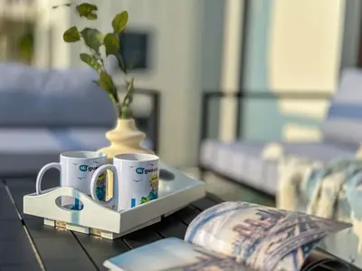 two coffee cups and a vase on a table at HiGuests - Family Dream Escape with Private Beach Access in Dubai