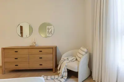 a bedroom with a dresser and a chair and a mirror at HiGuests - Family Dream Escape with Private Beach Access in Dubai