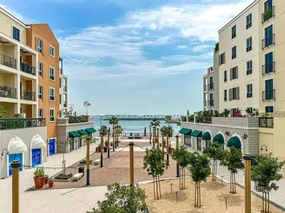 a street with buildings and trees in front of the water at HiGuests - Dream stay in our Cozy 2BR in La Rive Community in Dubai