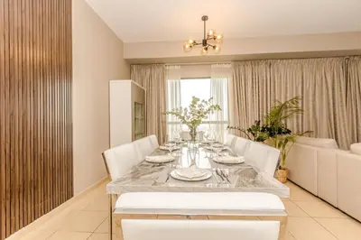 a dining room with a table and white chairs at GMA Rimal5 4BR Sea View in Dubai