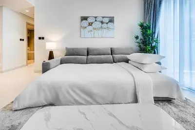 a white bedroom with a large white bed with pillows at Marina Vista 1BD with beach access in Beachfront in Dubai