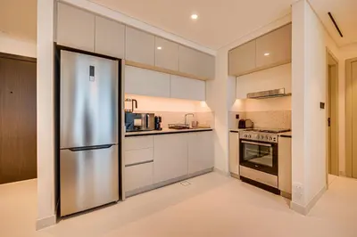 a kitchen with white cabinets and a stainless steel refrigerator at Marina Vista 1BD with beach access in Beachfront in Dubai