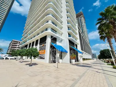a tall building with palm trees in front of it at Marina Vista 1BD with beach access in Beachfront in Dubai