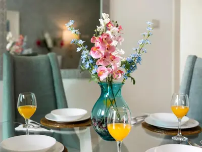 a vase with flowers on a table with two wine glasses at Luxury 1br Burj Khalifa View in Dubai