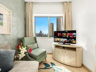 a living room with a tv and a chair and a window at Luxury 1br Burj Khalifa View in Dubai
