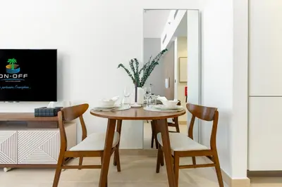 a dining room with a wooden table and chairs at ON OFF HH-Meydan One- Cozy STUDIO - Burj Khalifa & Lagoon view in Dubai