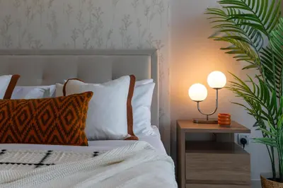 a bedroom with a bed with two lamps and a plant at ON OFF HH-Meydan One- Cozy STUDIO - Burj Khalifa & Lagoon view in Dubai