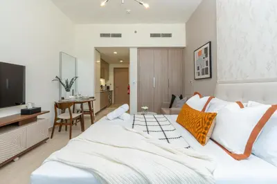 a bedroom with a bed and a television and a table at ON OFF HH-Meydan One- Cozy STUDIO - Burj Khalifa & Lagoon view in Dubai