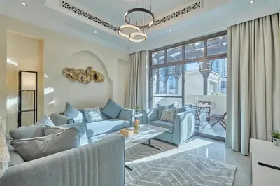 a living room with blue furniture and a large window at Golden Homes Souk Al Bahar Burj khalifa view Tajer residences 1BR Mint avenue Near , Dubai mall & burj khalifa in Dubai