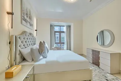 a white bedroom with a large bed and a mirror at Golden Homes Souk Al Bahar Burj khalifa view Tajer residences 1BR Mint avenue Near , Dubai mall & burj khalifa in Dubai