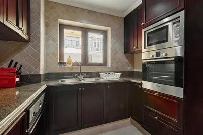 a kitchen with wooden cabinets and a sink and a window at Golden Homes Souk Al Bahar Burj khalifa view Tajer residences 1BR Mint avenue Near , Dubai mall & burj khalifa in Dubai