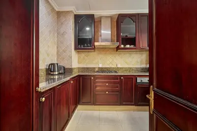 a large kitchen with wooden cabinets at Golden Homes Souk Al Bahar Burj khalifa view Tajer residences 1BR Mint avenue Near , Dubai mall & burj khalifa in Dubai