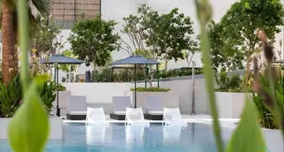 a pool with white chairs and umbrellas at Voguish studio! Walk to Burj Khalifasleeps 3! in Dubai