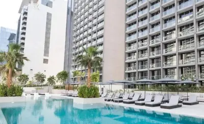a swimming pool in front of a building with chairs and umbrellas at Voguish studio! Walk to Burj Khalifasleeps 3! in Dubai
