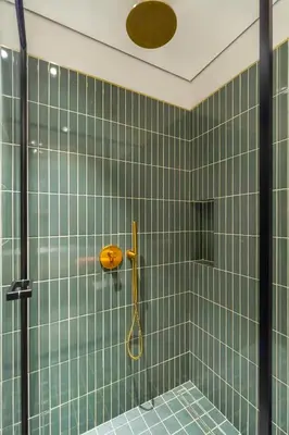 a green tiled bathroom with a shower with a racket at FAM Living - Upside Living - WFH Friendly-Business Bay in Dubai