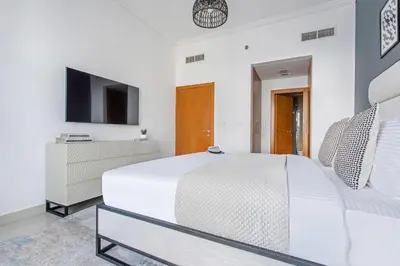 a white bedroom with a bed and a tv at Frank Porter - Ocean Heights in Dubai