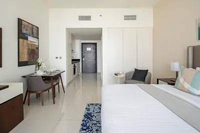 a bedroom with a bed and a table and a kitchen at Frank Porter - Avanti Tower in Dubai