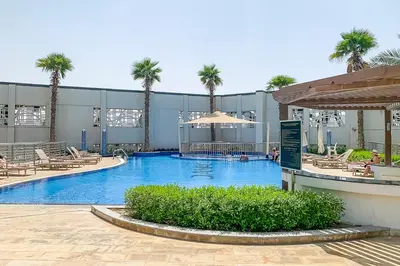 a large swimming pool with palm trees in front of a building at Frank Porter - Avanti Tower in Dubai