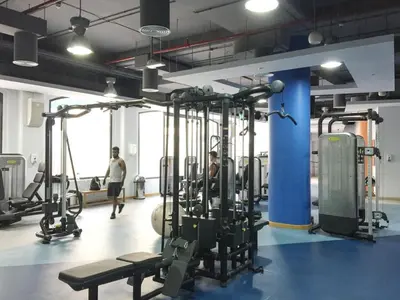 a gym with several tread machines and people in the background at GuestReady - Beachside Escape near Marina Beach in Dubai