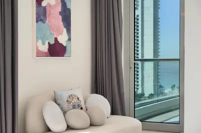 a white chair with a pillow in a room with a window at Iolanda Home in Dubai