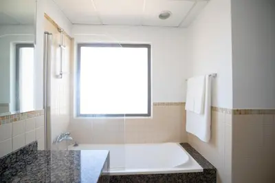 a white bathroom with a tub and a window at GMA Amwaj 2BR Sea View High Floor in Dubai