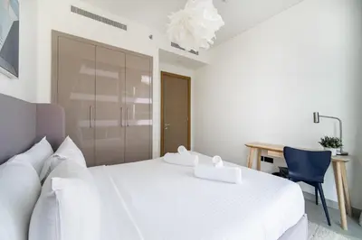 a white bedroom with a white bed and a desk at SettlerHomes - 2BR Downtown Haven, Ideal For Family Comfort in Dubai