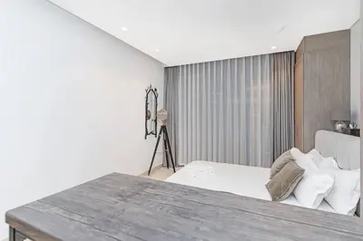 a white bedroom with a bed and a table at Designer Glam Studio Steps from Burj Khalifa in Dubai