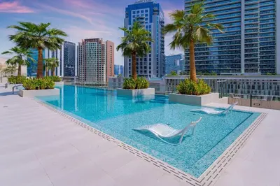 a swimming pool on the roof of a building with palm trees at Designer Glam Studio Steps from Burj Khalifa in Dubai
