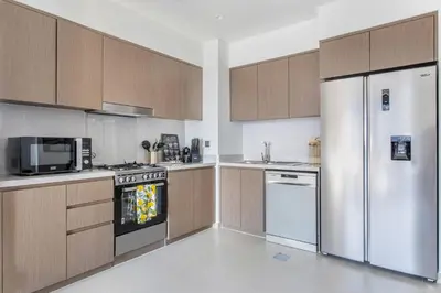 a kitchen with stainless steel appliances and wooden cabinets at Frank Porter - Act One Act Two T1 in Dubai