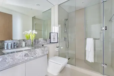 a bathroom with a toilet and a glass shower at Frank Porter - Act One Act Two T1 in Dubai