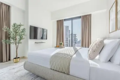 a white bedroom with a large bed and a window at Frank Porter - Act One Act Two T1 in Dubai