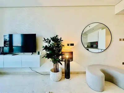 a living room with a large mirror and a tv at Chic Studio with Burj Views at Sterling by Omniyat in Dubai