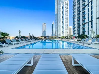 a large swimming pool with lounge chairs and buildings at Amazing Apartment with City Views in Downtown 164BC-2 in Dubai
