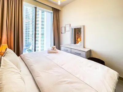 a bedroom with a large white bed and a window at Cozy Apartment with City Views Next to Burj Khalifa 166FO1-2 in Dubai