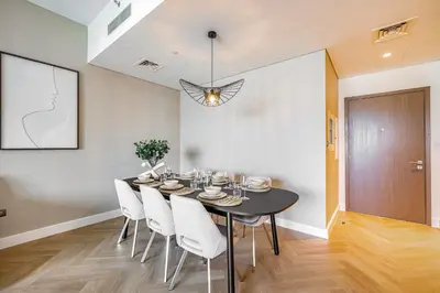 a dining room with a black table and white chairs at Daniels 3BR Urban Retreat with Downtown Views in Dubai