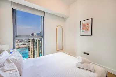 a white bedroom with a large window and a bed at Daniels 3BR Urban Retreat with Downtown Views in Dubai