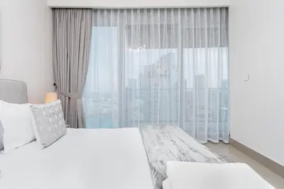 a bedroom with a white bed and a large window at WhiteSage - Opera Grand Elegance 3BR with Burj Khalifa Views in Dubai