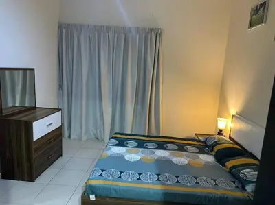 a bedroom with a bed and a dresser and a window at Stylish 1bhk at silicon oasis in Dubai
