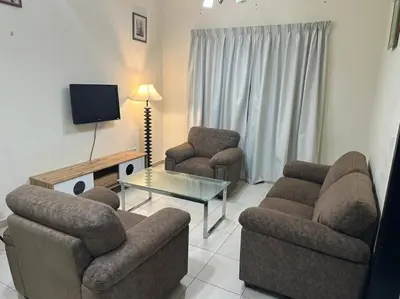 a living room with two chairs and a table and a tv at Stylish 1bhk at silicon oasis in Dubai