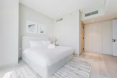 a white bedroom with a large white bed and a rug at Stayis -Luxurious 2BR Apartment with breathtaking ocean and Marina View in Dubai