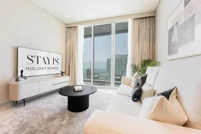 a living room with a white couch and a large window at Stayis -Luxurious 2BR Apartment with breathtaking ocean and Marina View in Dubai