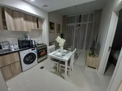 a small kitchen with a table and a stove and a microwave at StoneTree - Furnished 1BR in Golf Vita A in Dubai