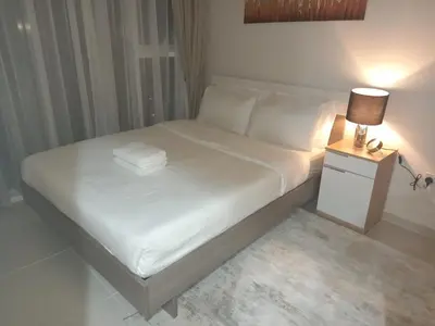 a bed with white sheets and a lamp on a night stand at StoneTree - Furnished 1BR in Golf Vita A in Dubai