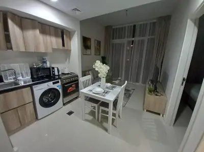 a kitchen with a table and a stove and a microwave at StoneTree - Furnished 1BR in Golf Vita A in Dubai