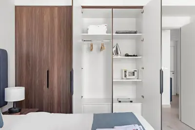 a bedroom with a white bed and a wooden closet at StoneTree - Furnished 1BR in Madinat Jumeirah in Dubai